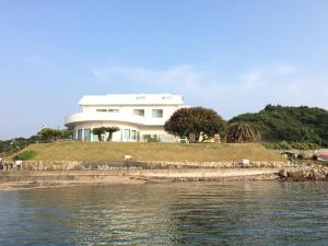 a large white house on a hill next to the water at Shirahama Seaside Villa in Tanabe