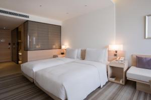 a bedroom with a large white bed and a couch at Hotel COZZI Zhongxiao Taipei in Taipei