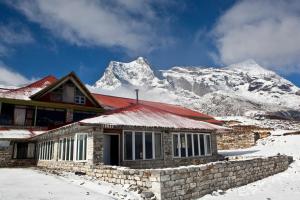 une maison en face d'une montagne enneigée dans l'établissement Mountain Lodges of Nepal - Kongde, à Kongde
