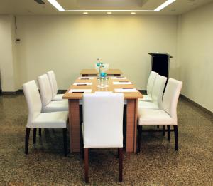 una sala de conferencias con mesa de madera y sillas blancas en Hotel Ivory 32 en Nueva Delhi