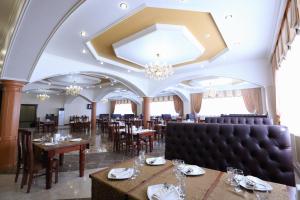 a restaurant with tables and chairs and a chandelier at Hotel Bahetle in Ekibastuz