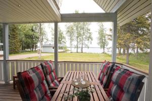 a table and chairs on a porch with a view of the water at Villa Aurela in Rovaniemi