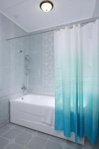 a bathroom with a tub and a shower curtain at Hotel Bahetle in Ekibastuz