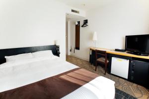 Dormitorio con cama, escritorio y TV en Sapporo Tokyu REI Hotel, en Sapporo