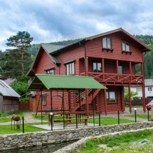 ein großes Holzhaus mit grünem Dach in der Unterkunft Svitlana in Tatariw