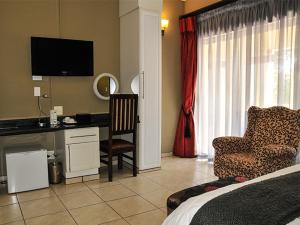 a bedroom with a bed and a desk and a chair at 2Ten Hotel in Sibasa