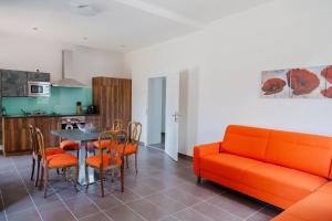 ein Wohnzimmer mit einem orangenen Sofa, einem Tisch und Stühlen in der Unterkunft Haus Bachforelle in Millstatt