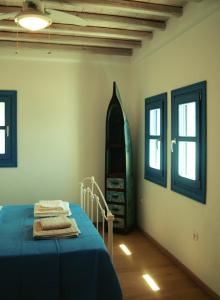 1 dormitorio con 1 cama azul y 2 ventanas en Almyra Yellow Villa en Kithnos