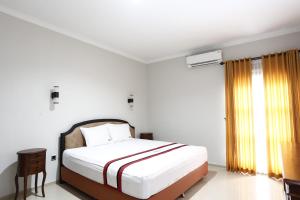 a white bedroom with a bed and a window at RedDoorz Plus near Adisucipto Airport 2 in Yogyakarta