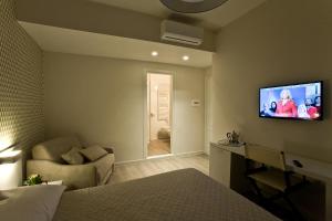 マテーラにあるDomus Romaのソファ付きのベッドルーム、壁にテレビが備わります。