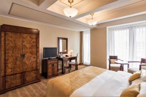 a bedroom with a bed and a desk and a television at Majestic Plaza Hotel Prague in Prague