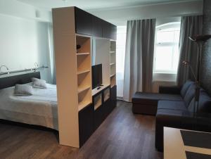 een slaapkamer met een bed en een tv en een bank bij Apartment Satama in Kuopio