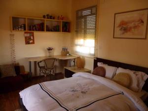 a bedroom with a bed and a desk and a table at Margo Zimmer in Midreshet Ben Gurion