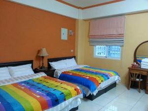 台東市的住宿－蕃茄咖啡民宿，一间卧室配有两张带彩色毯子的床