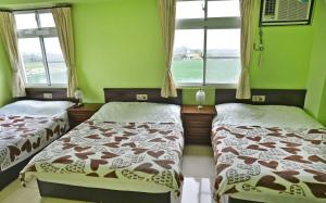 Dos camas en una habitación con paredes y ventanas verdes. en Tomato Coffee B&B, en Taitung