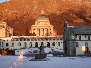 a building with a clock tower and a building with a fountain at Santuario di Oropa in Biella