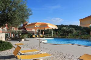 a pool with an umbrella and some chairs and a table at Il Parco Sul Mare Resort & SPA in Tortoreto Lido