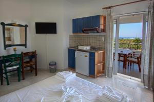 a room with a kitchen and a table with a balcony at Pinelopi Apartments in Georgioupolis