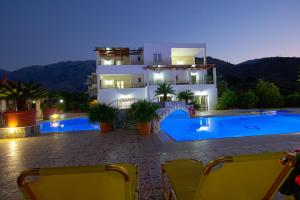 a villa with a swimming pool at night at Pinelopi Apartments in Georgioupolis