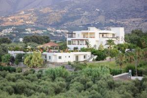 a large white house on top of a hill at Pinelopi Apartments in Georgioupolis