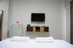 a bedroom with a white bed with a tv on the wall at Paru Ville in Nakhon Ratchasima