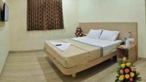 ein Schlafzimmer mit einem Bett und einem Tisch mit Blumen in der Unterkunft SK Residency Unit 2 in Coimbatore