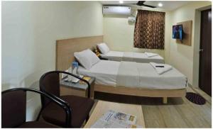 ein Hotelzimmer mit 2 Betten und einem Stuhl in der Unterkunft SK Residency Unit 2 in Coimbatore