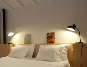 a bedroom with a bed with white pillows and two lamps at Coimbra Vintage Lofts Apartments in Coimbra