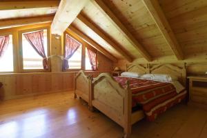 una camera da letto in una baita di tronchi con letto e finestre di Agritur Manoncin a Daone