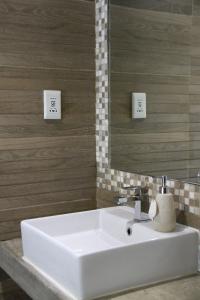 La salle de bains est pourvue d'un lavabo blanc et d'un miroir. dans l'établissement Sea Wind Self Catering Cottages, à Swakopmund
