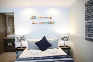 a bedroom with a bed with two lamps and towels at Sea Wind Self Catering Cottages in Swakopmund
