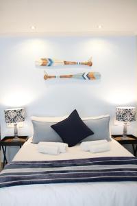a bedroom with a bed with two lamps and two surfboards on the wall at Sea Wind Self Catering Cottages in Swakopmund