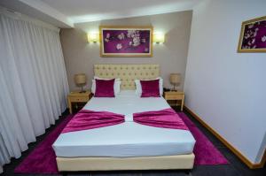 una camera da letto con un grande letto bianco con lenzuola viola di Vivi Hotel a Praia