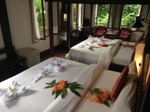 three beds in a room with flowers on them at Khoum Xieng Thong Boutique Villa in Luang Prabang