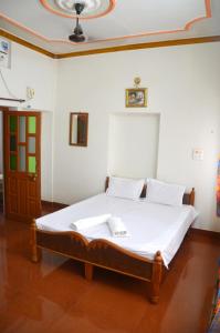 1 cama con sábanas blancas y almohadas en una habitación en Gajanand Guest House, en Jaisalmer