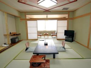 a room with a table and chairs and a television at Nisshokan Shinkan Baishokaku in Nagasaki
