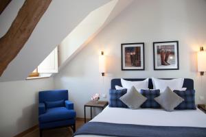 - une chambre avec un lit et une chaise bleue dans l'établissement Manoir de Surville, à Surville