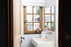 ein Bad mit einem Waschbecken, einem Spiegel und einem Fenster in der Unterkunft Manoir de Surville in Surville