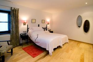 a bedroom with a large bed with white sheets at Hotel rural L'Anceo in Cibuyo