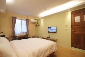 1 dormitorio con 1 cama blanca y TV en Heaven Bird B&B en Nanzhuang