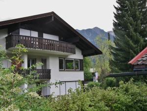 a white house with a balcony and trees at Alpenflair Ferienwohnungen Whg 101+213 in Oberstdorf