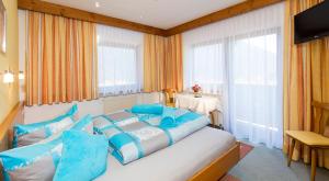 a bedroom with a large bed with blue pillows at Gasthof Pension Granstein in Sölden