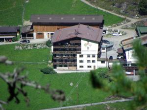 ein Gebäude mit einem Dach auf einem grünen Feld in der Unterkunft Gästehaus Berghof Schöpf in Längenfeld