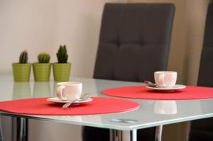 プラハにあるGE Apartmentsのテーブルの上に赤皿2皿とカップ