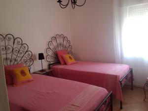 サグレスにあるCasa de Sagres- Good Swellのピンクのシーツが備わる客室内のベッド2台