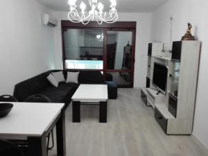 a living room with a black couch and a tv at Апартамент Дарко in Pomorie