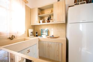 uma cozinha com armários de madeira e um frigorífico branco em Mera Beachfront House - Falasarna em Falasarna
