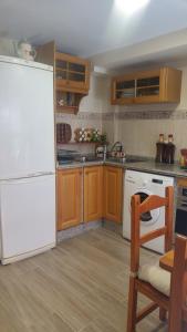 cocina con nevera blanca y armarios de madera en Casa Dale, en Mairena del Aljarafe