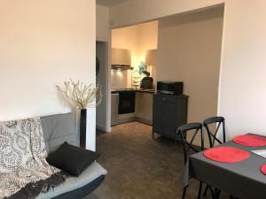 a living room with a couch and a table and a kitchen at Vue mer à Arromanches in Arromanches-les-Bains