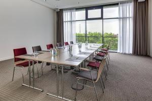 una gran sala de conferencias con una mesa larga y sillas en IntercityHotel Duisburg, en Duisburg